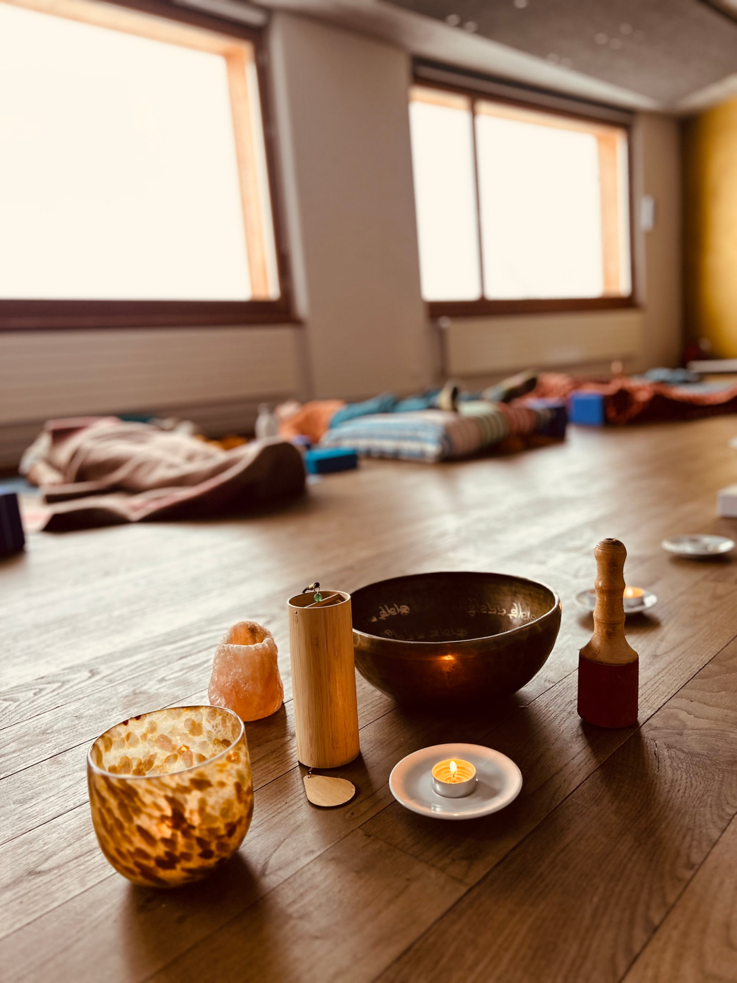 Klangschale, Kerze und Salzlampe auf dem Studioboden, dahinter ruht die Gruppe