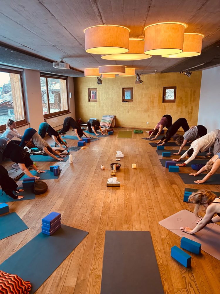 Students in downward facing dog in a warmly lit room