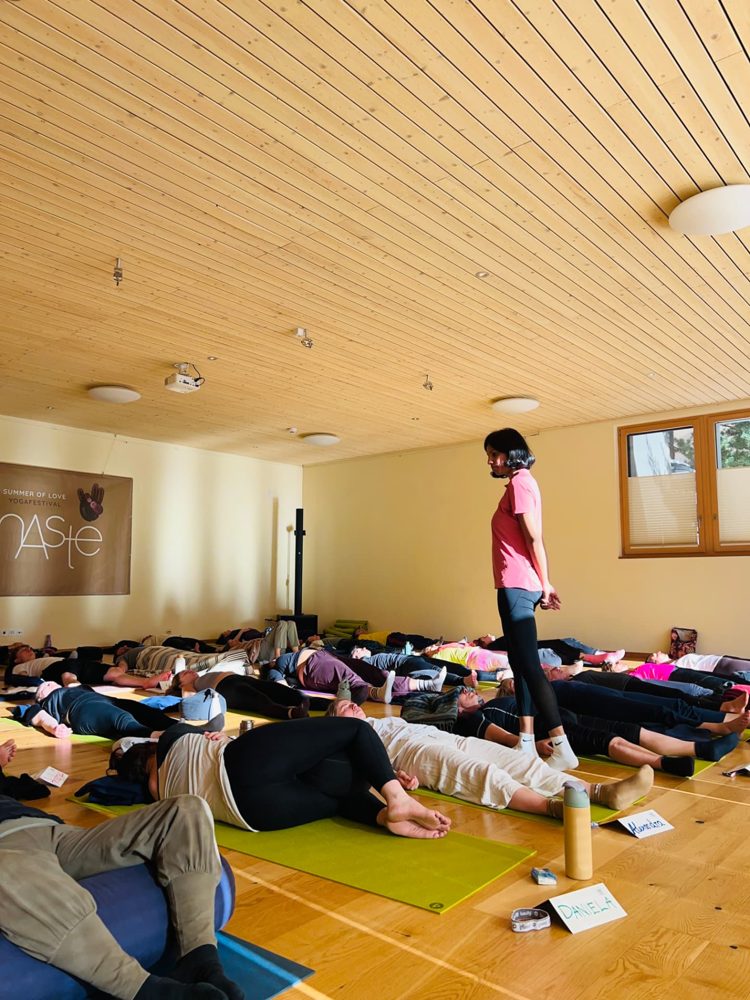 Gana standing among students resting in savasana